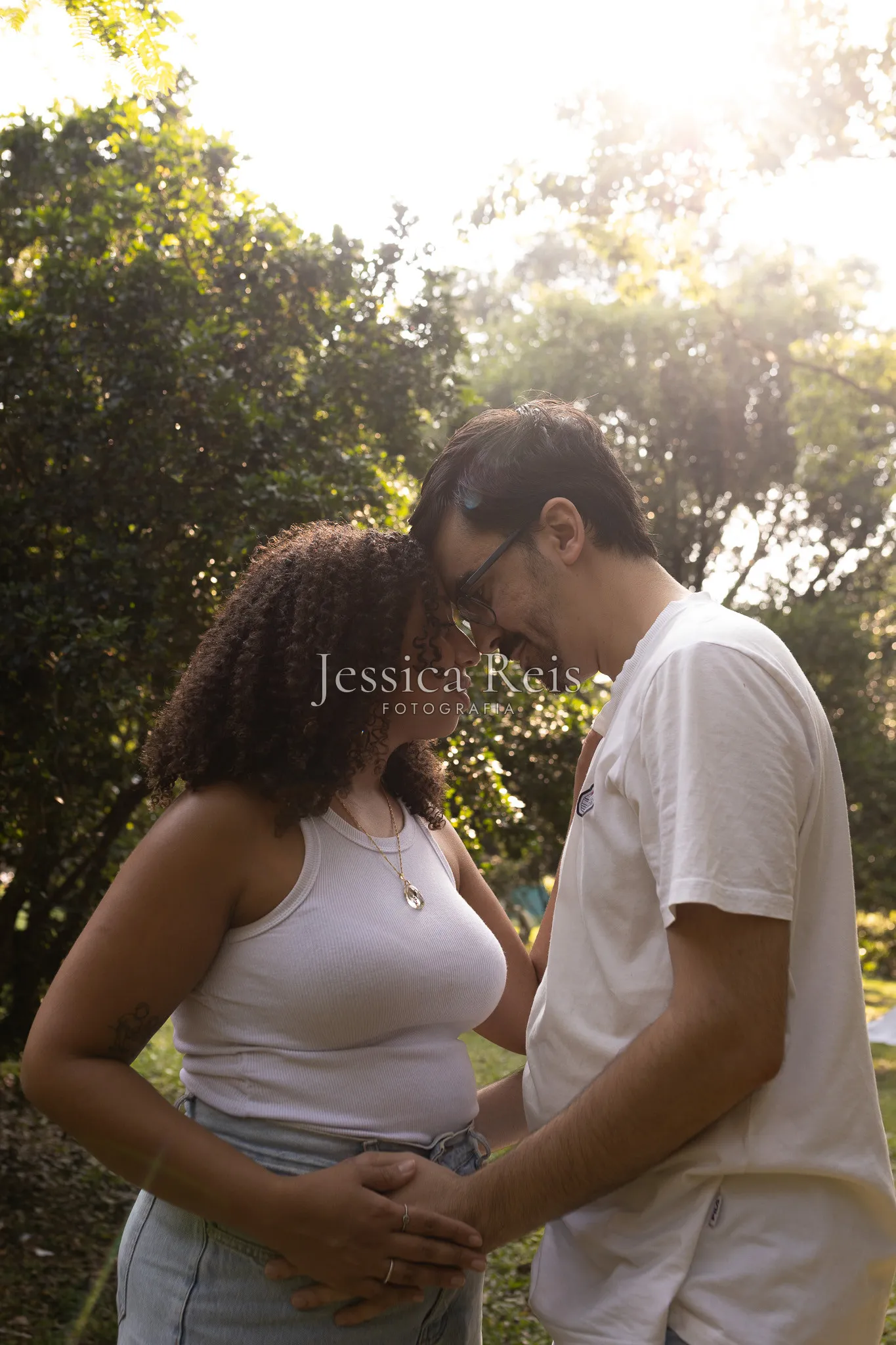 Casal testa com testa em contraluz antes do chá revelação, ao ar livre