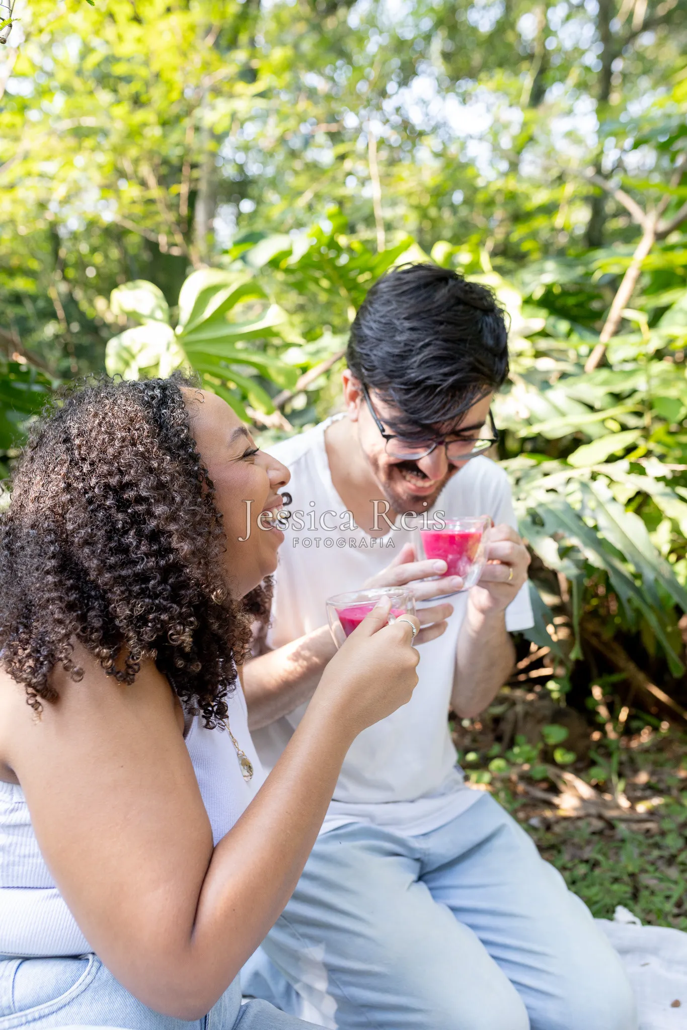 Casal comemorando com as bebidas rosa, é menina, no chá revelação