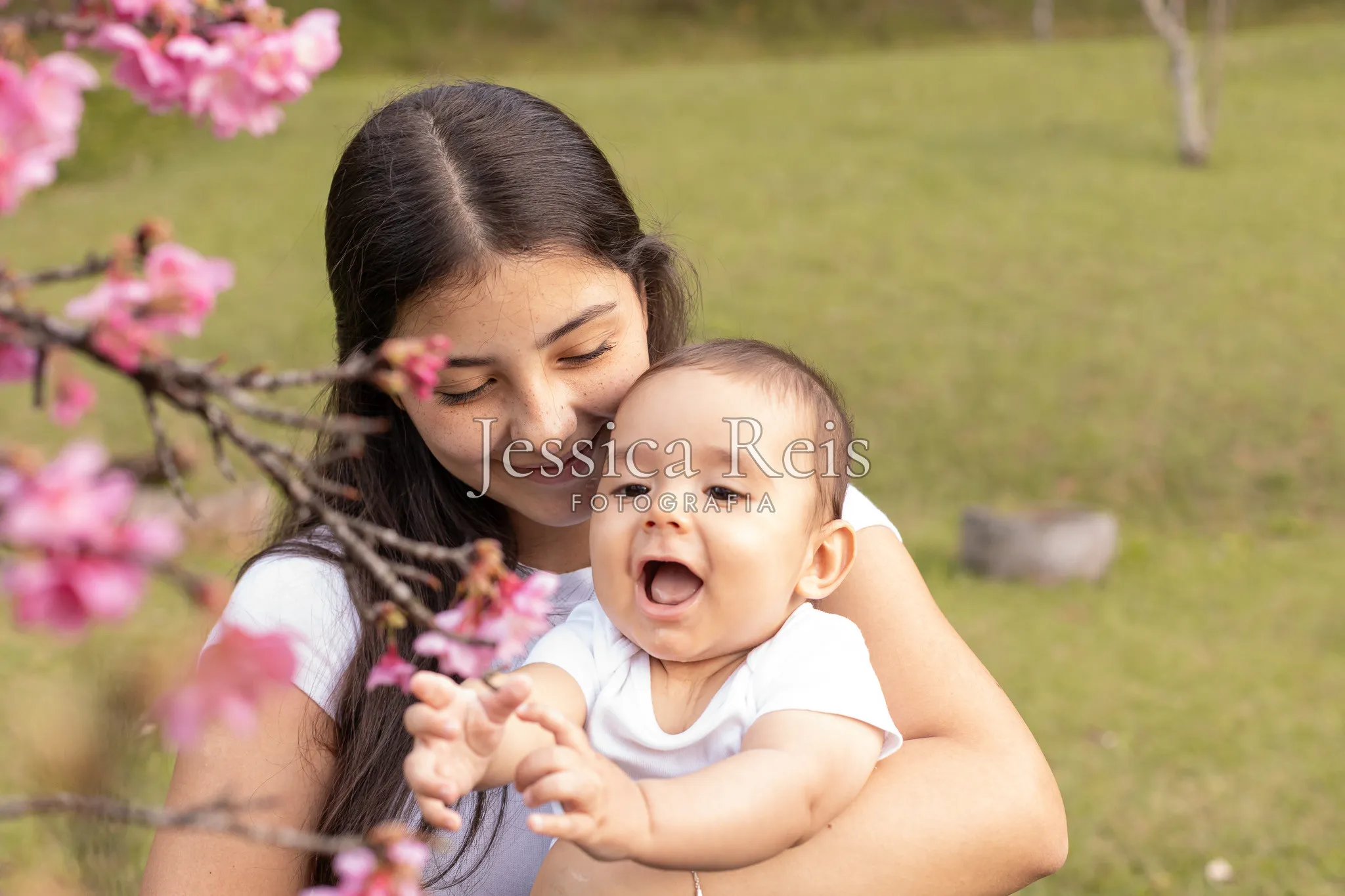 Mãe e bebê entre as flores de cerejeira, ensaio de família ao ar livre