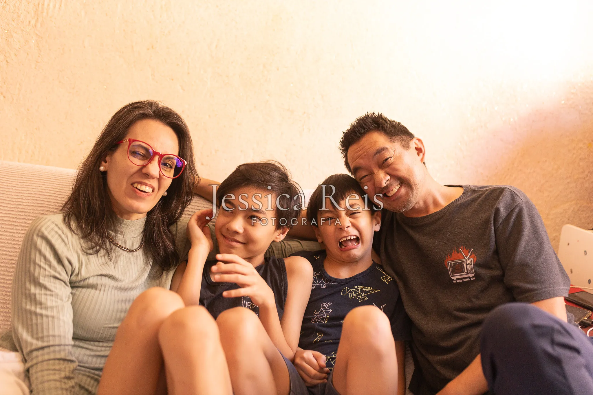 Família rindo junta no sofá de casa, ensaio de família lifestyle