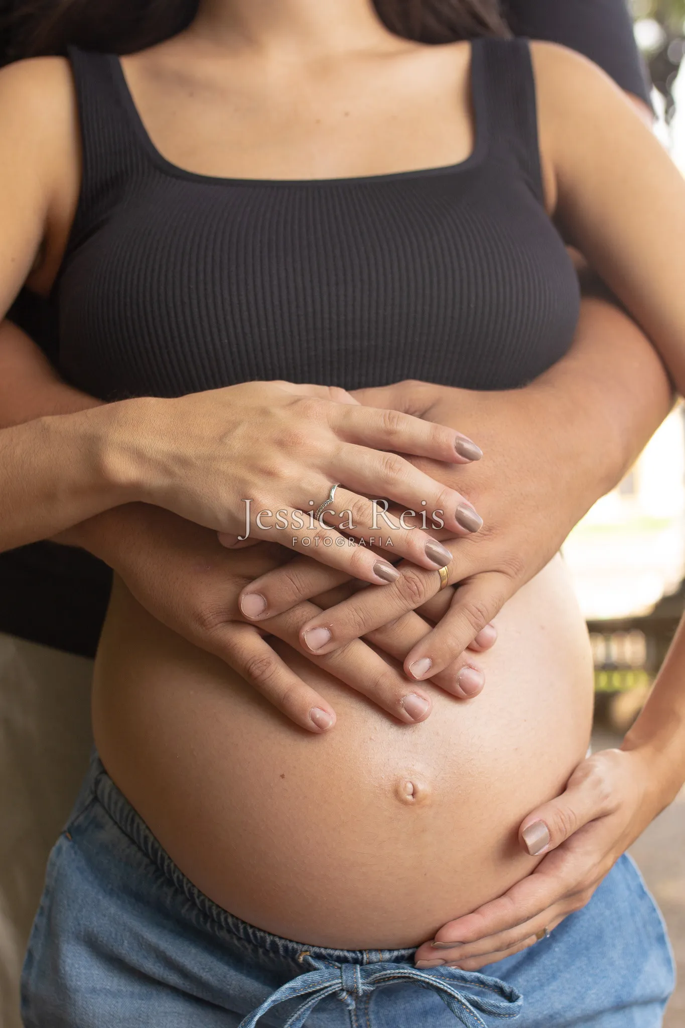 Mãos da gestante e do pai sobre a barriga, ensaio gestante ao ar livre no parque do Ipiranga