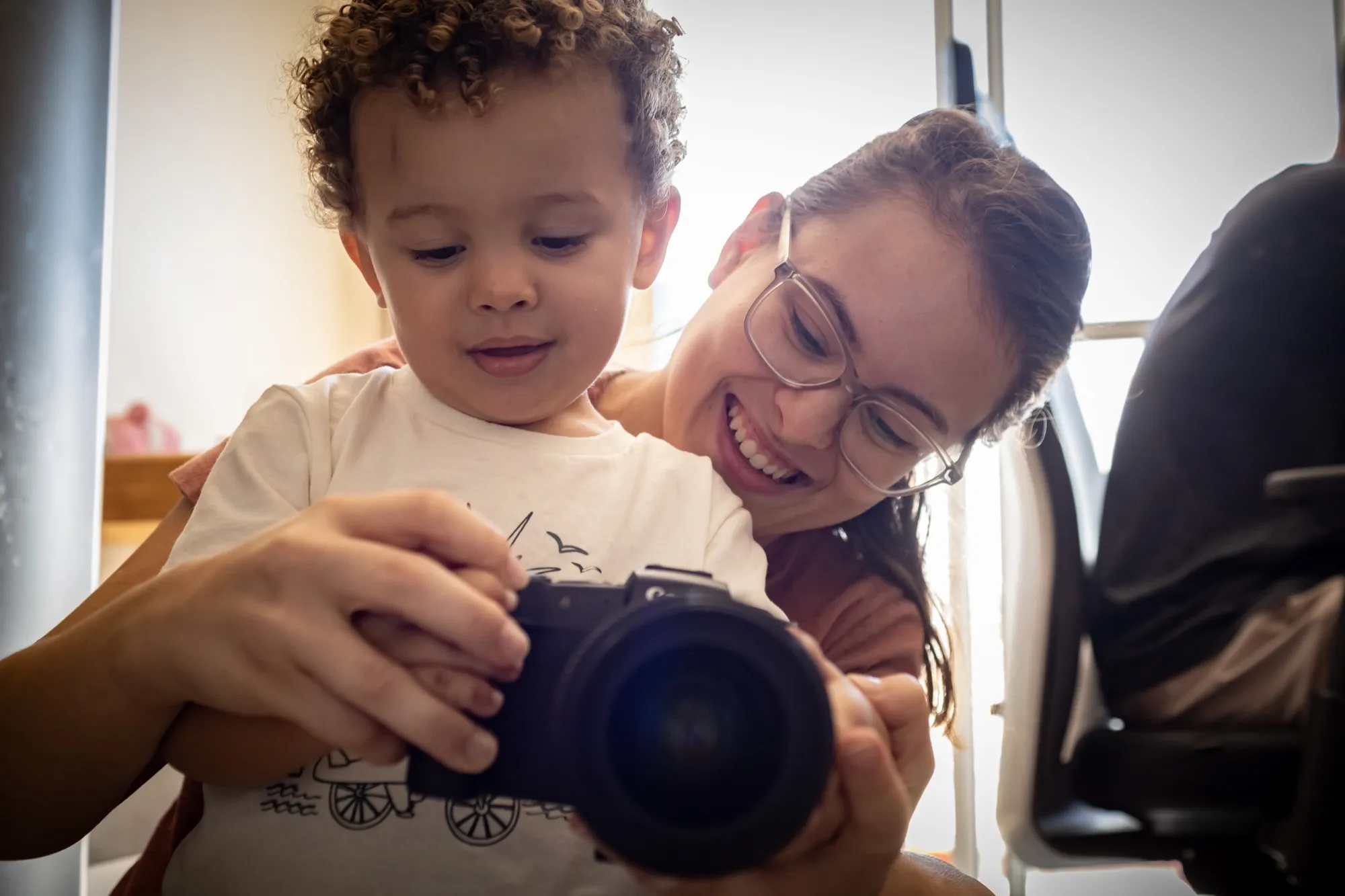 A fotógrafa Jessica Reis sorrindo ao lado do filho, que segura a câmera