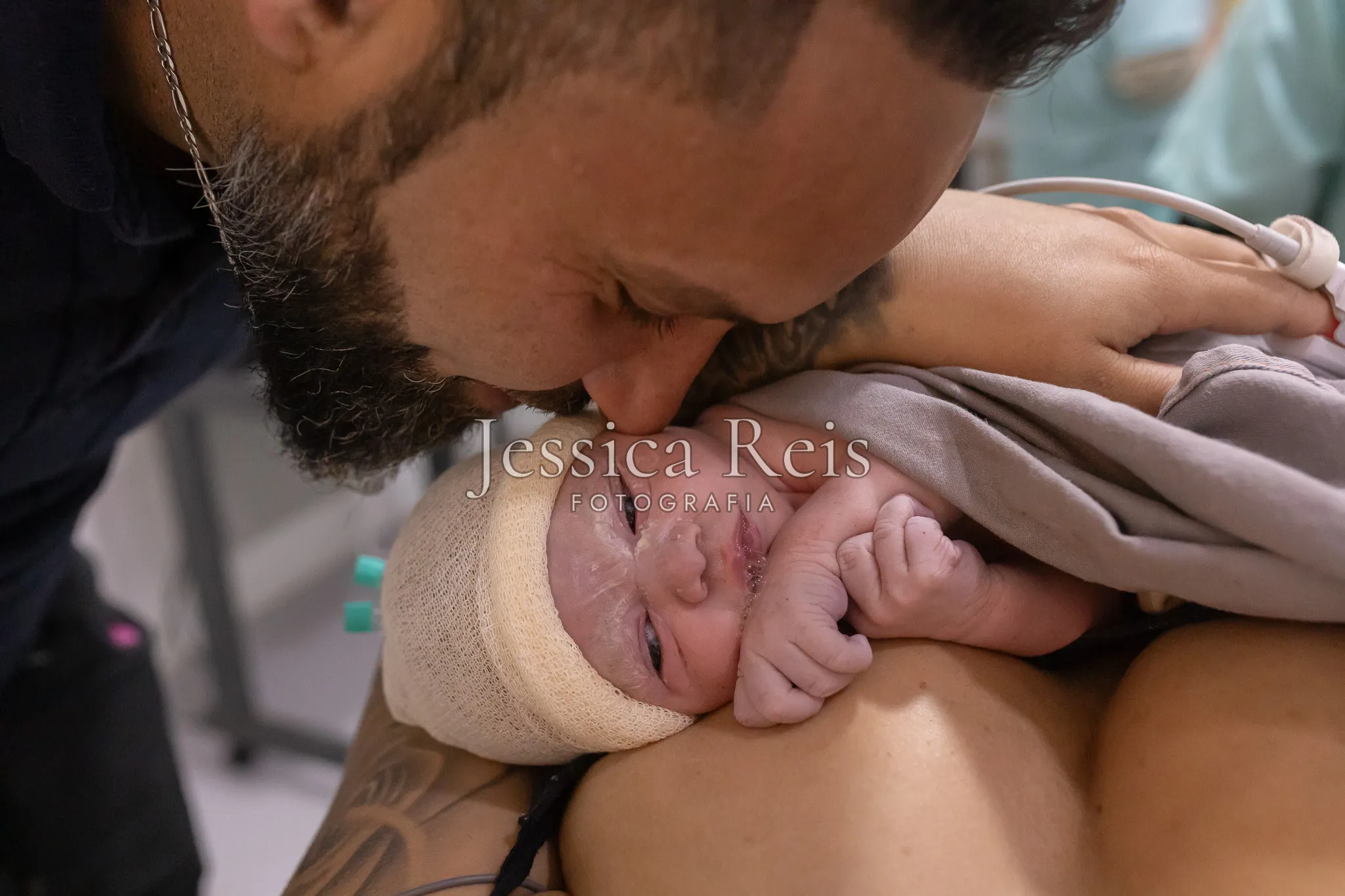 Pai beijando o recém-nascido no colo da mãe, parto humanizado com doula no Amparo Maternal
