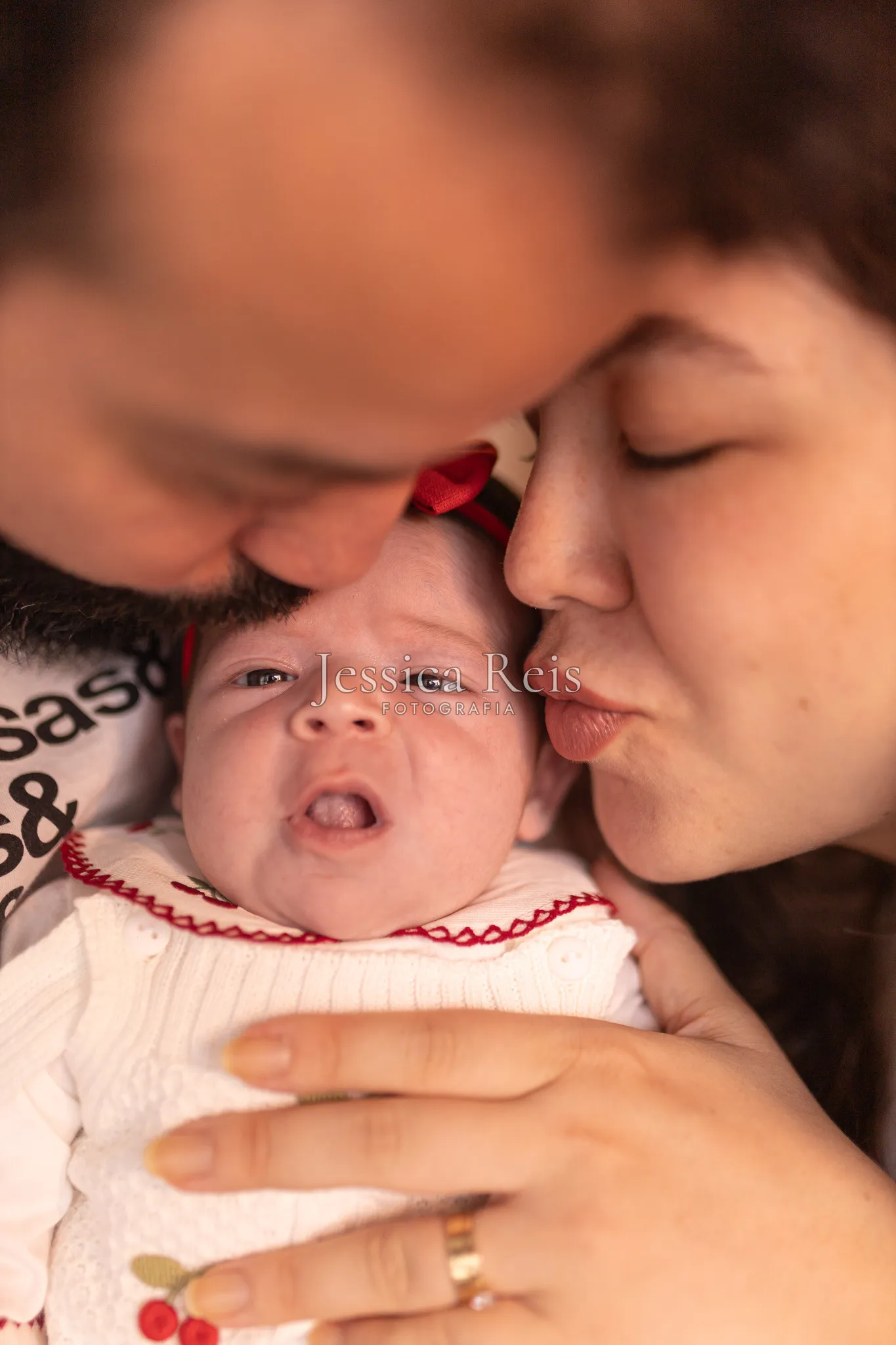 Pais beijando a recém-nascida no ensaio newborn em casa